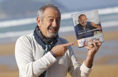 El cocinero Karlos Arguiñano posa junto a su último libro con la playa de Zarautz al fondo.