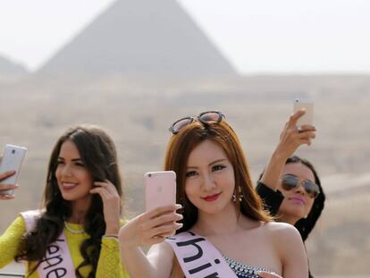 Un grupo de misses se toman varios selfis frente a las pirámides de Egipto.