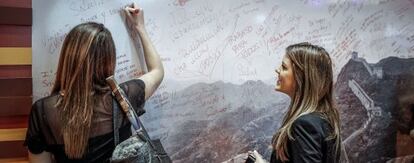Dos mujeres firman en un mural de la Gran Muralla China en Fitur.