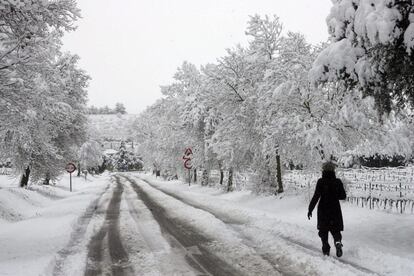 Una mujer camina por una carretera nevada en las inmediaciones de l'Espluga de Francoli, uno de los pueblos de Tarragona afectados por el temporal de nieve.