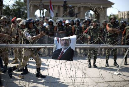 Un cartel del derrocado presidente egipcio Mohamed Morsi visto desde el alambre que protege la sede de la Guardia Republicana en El Cairo, el 5 de julio de 2013. El Ejército asegura que sus tropas no ha usado munición real contra los partidarios del presidente depuesto Mohamed Mursi que se manifestaban en el barrio cairota de Ciudad Naser, frente al edificio de esa unidad militar encargada de la escolta y la seguridad presidencial.