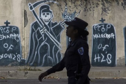 Uma oficial de policial caminha em um bairro controlado pela mara