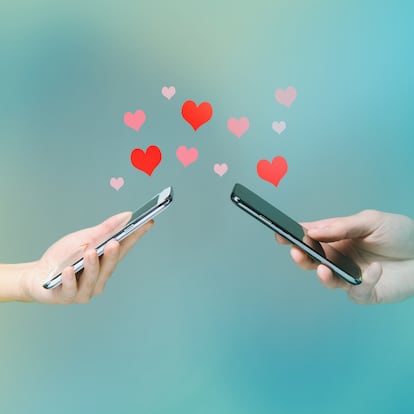Young man and woman's hands holding smart phones with hearts floating over