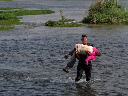 Un migrante venezolano cruza el Río Bravo con una mujer de la tercera edad en brazos el 26 de mayo.