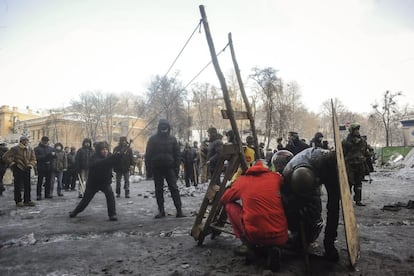 Manifestantes lanzan objetos contra la policía en el quinto día de enfrentamientos en Kiev.