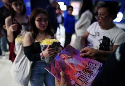 Varios fans de Taylor Swift recogen un póster a la entrada de una sala para ver su 'The Eras Tour' en Ciudad de México, el 13 de octubre de 2023.