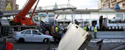 Los operarios retiran los restos del paso peatonal elevado que se ha caído esta tarde sobre la A-7, en Mijas.