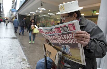 Un limpiabotas lee una portada que refleja la derrota argentina ante Chile.