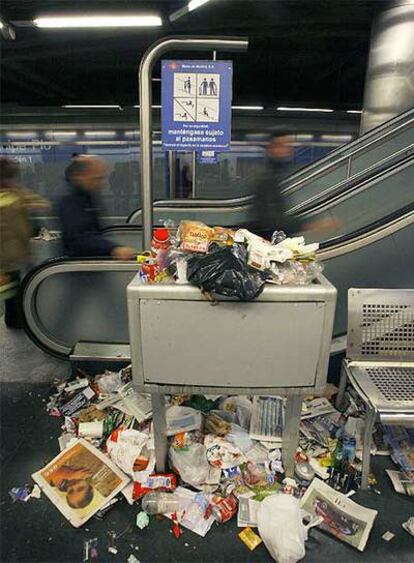 Varios usuarios del Metro de Madrid caminan entre la basura.