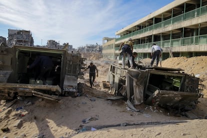 Diversi palestinesi camminano sui resti di veicoli militari blindati abbandonati dopo l'offensiva israeliana, questo lunedì a Rafah.