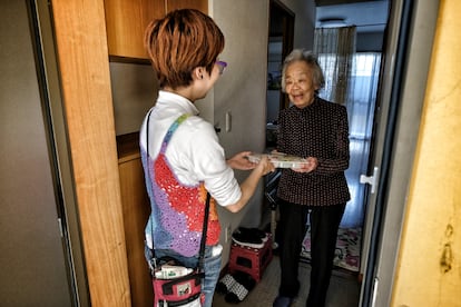 Asahi (32 años) trabaja desde 2015 apoyando a los residentes más mayores en Nagaya. Aquí entrega una ración de comida preparada a Kamimura, de 90 años. 