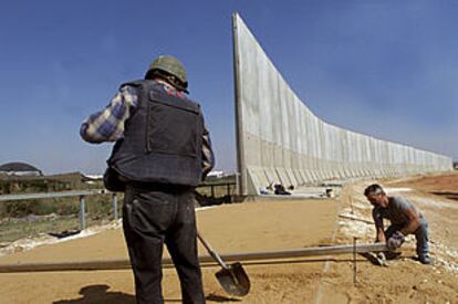Dos trabajadores israelíes, ayer, construyen un muro que separará la ciudad palestina de Kalkilia de Israel.