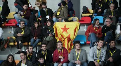 Assistents segueixen l'assemblea al costat d'una bandera independentista.