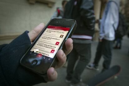 Una persona sostiene su tel&eacute;fono en la puerta de un colegio. 