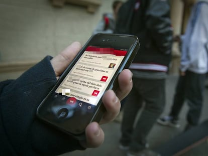 Una persona sostiene su teléfono en la puerta de un colegio. 