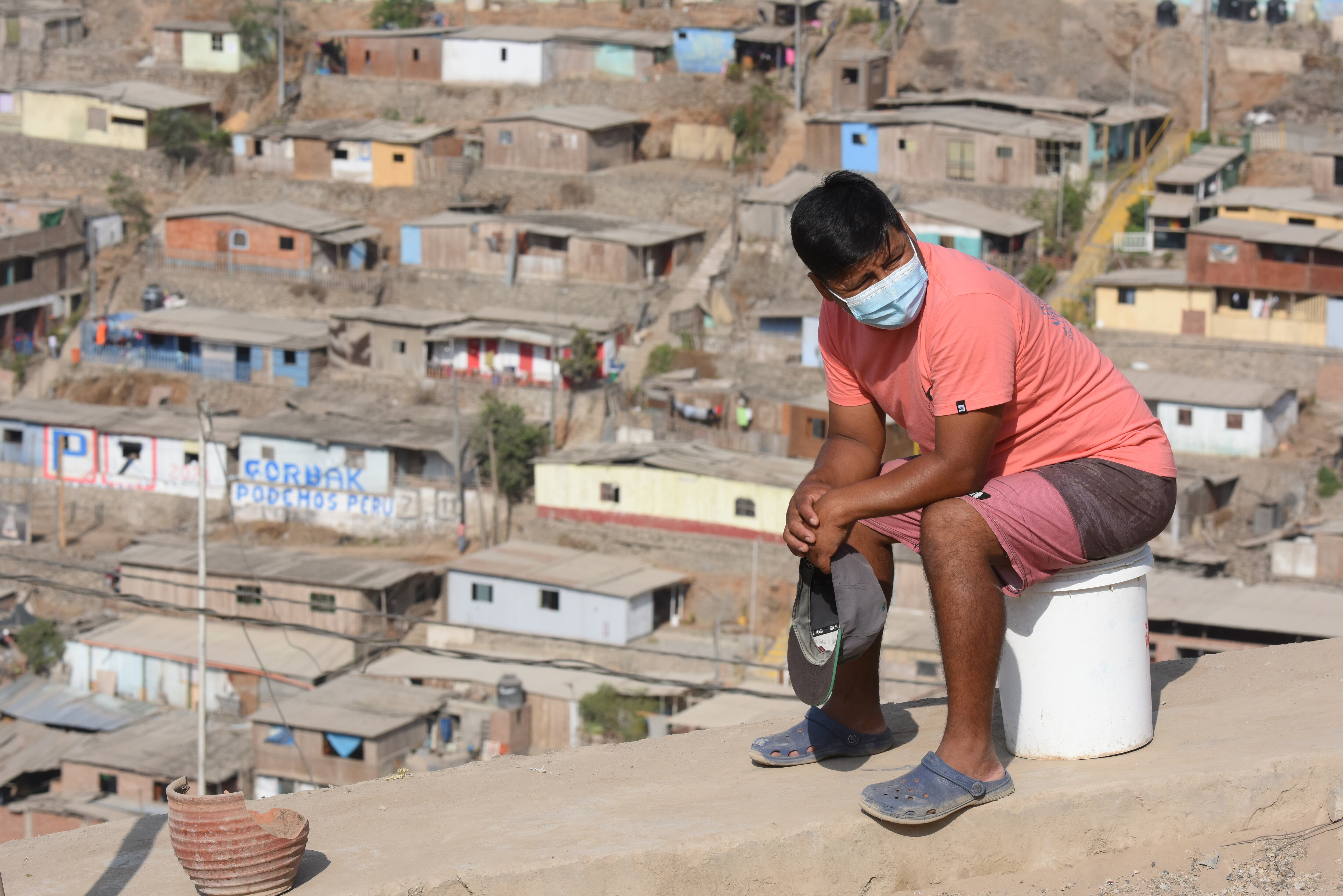 Un hombre sentado con vistas a una Lima árida detrás.