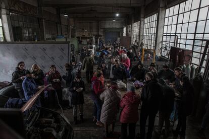 Voluntarios comen dentro de una antigua fabrica de muebles convertida en industria de guerra en Zaporiyia. Esta localidad del sureste de Ucrania fue objeto de una ofensiva a comienzos de marzo que hizo saltar todas las alarmas, ya que el Ejército ruso se hizo con el control de la central nuclear, la mayor de Europa y una de las más grandes del mundo, con seis reactores atómicos, tras un ataque que provocó un incendio en uno de sus edificios, sin que se produjeran escapes radiactivos pero sí el temor a un desastre nuclear.