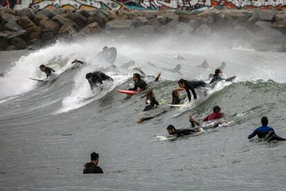 Varias decenas de personas practican surf en una playa de Barcelona (España).