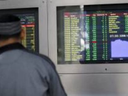 Dos inversores observan unos monitores en los que se muestran los valores de la Bolsa de Singapur. EFE/Archivo