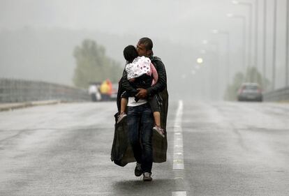 Um refugiado sírio beija a sua filha enquanto caminha no meio de uma tormenta para a fronteira da Grécia com a Macedônia, perto da vila de Idomeni.