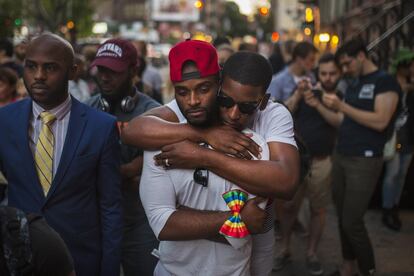 Dos jóvenes se abrazan frente a un monumento improvisado en Nueva York para recordar a las víctimas de un tiroteo masivo en Orlando.