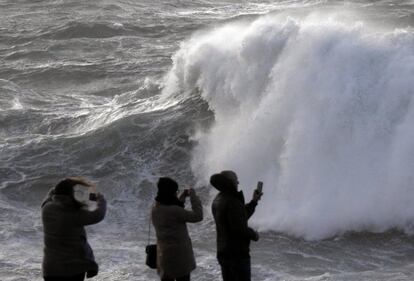 Varios turistas graban las olas esta tarde en la costa de Muxía (A Coruña).