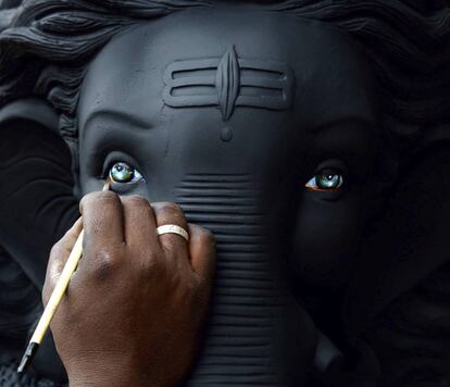 Un artista da los toques finales al dios hindú con cabeza de elefante, Ganesha, durante los preparativos para el próximo festival de Ganesh Chaturthi, en un taller de carretera en Bangalore, (India).