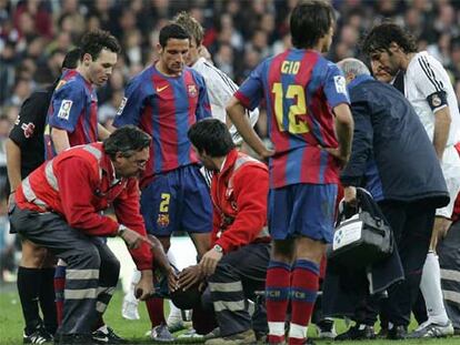 Los jugadores de los dos equipos observan a Eto'o en la camilla en la que abandonó lesionado el terreno de juego.