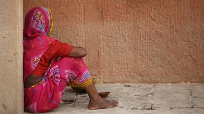 Una mujer sentada en una acera, en India.