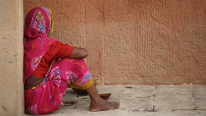 Una mujer sentada en una acera, en India.