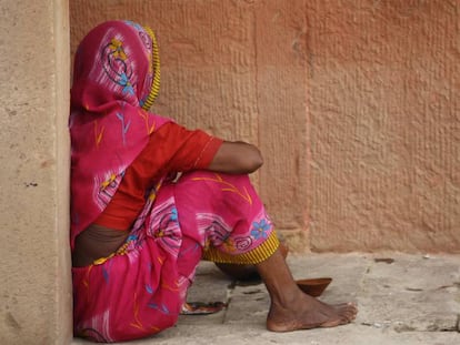 Una mujer sentada en una acera, en India.