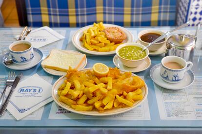 Un plato de 'fish', 'chips' y puré de guisantes. Al fondo, un plato de pastel de ternera y salsa espesa, junto con una tetera de té Tetley's.