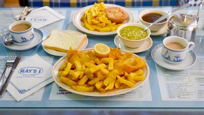 Un plato de 'fish', 'chips' y puré de guisantes. Al fondo, un plato de pastel de ternera y salsa espesa, junto con una tetera de té Tetley's.