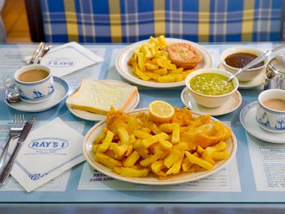 Un plato de 'fish', 'chips' y puré de guisantes. Al fondo, un plato de pastel de ternera y salsa espesa, junto con una tetera de té Tetley's.