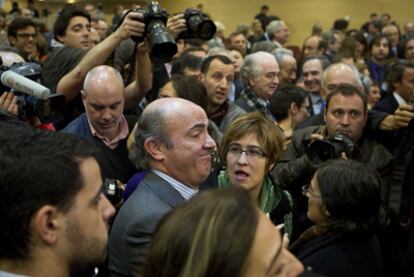 El ministro de economía, Luis de Guindos (en el centro), rodeado de periodistas, ayer en el ministerio.