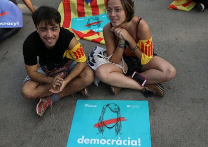 Una pareja de jóvenes miran una pantalla frente al Parlament.  