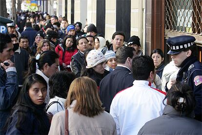 Un policía controla el acceso al consulado de Ecuador ante una larga fila de personas que quieren regularizar su situación en España.