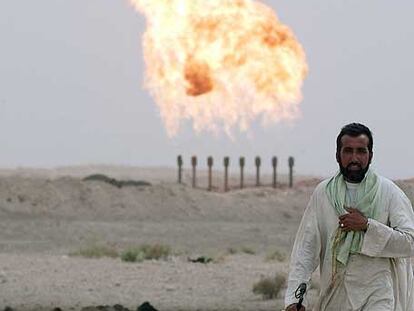 Un hombre con sus ovejas cerca de una planta de gas en Irak.