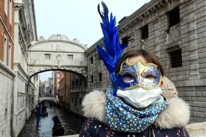 Un joven turista con una máscara protectora y una máscara de Carnaval visita las calles de Venecia, el 24 de febrero.