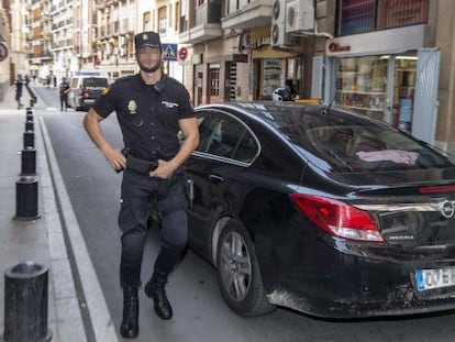 Un policia custodia un dels cotxes que traslladen els agents detinguts.