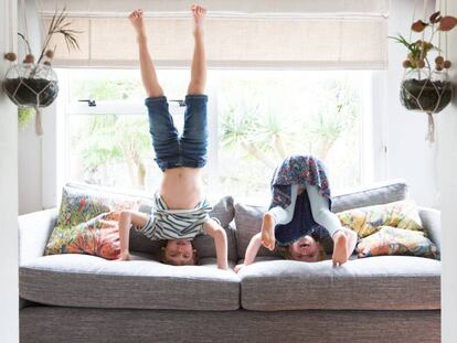 Dos niños juegan en el sillón de su casa. 