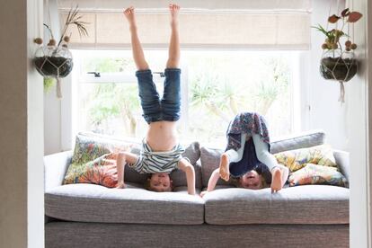 Dos niños juegan en el sillón de su casa. 