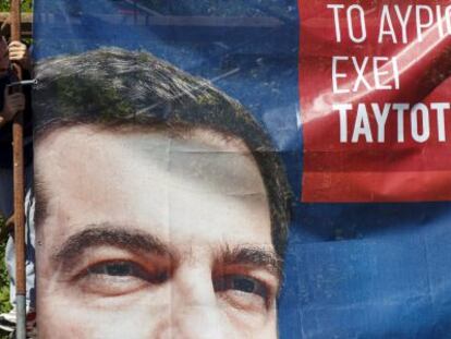 Un trabajador tras un cartel electoral de Syriza, hoy en Atenas