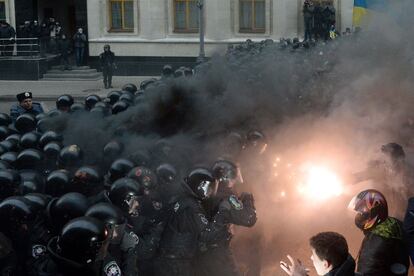 Un manifestante sostiene una bengala durante los choques con la polic&iacute;a antidisturbios en Kiev.