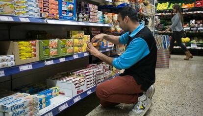 Un franquiciado coloca los productos en las estanter&iacute;as de un supermercado de Sants.