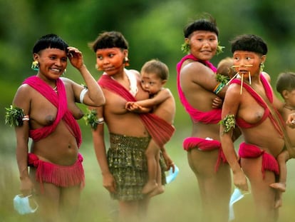 Integrantes del pueblo yanomami sujetan mascarillas y cargan a sus bebés el 1 de julio de 2020 en la región de Surucucu, municipio de Alto Alegre, estado de Roraima (Brasil). El coronavirus ha llegado a la mayor tierra indígena de Brasil y amenaza a los históricos guardianes de la Amazonía.