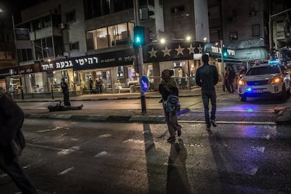 <p>Un solicitante de asilo eritreo cruza una calle acordonada del sur de Tel Aviv en la que un equipo de artificieros israelíes desmonta un objeto sospechoso, mientras un israelí en estado de embriaguez que había traspasado el perímetro yace en el suelo.</p> <p>A este distrito llegaron por primera vez muchos demandantes de asilo después de cruzar la frontera entre Egipto e Israel y de que los liberasen del centro de internamiento de extranjeros del sur del país. Gran parte de esta comunidad se ha instalado en la zona del sur de la ciudad, en la que abundan los pequeños negocios dirigidos por miembros de la misma. Sin embargo, en general, la sociedad israelí discrimina a estas personas, que permanecen atrapadas en un limbo legal sin que las instituciones del Estado las reconozcan como solicitantes de asilo.</p>