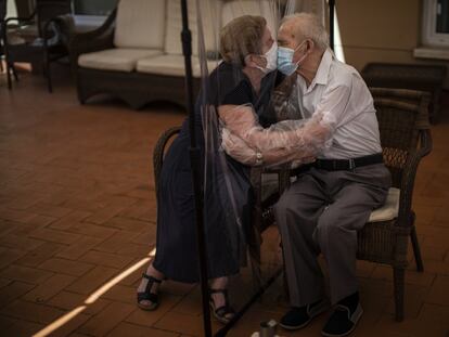 Agustina Cañamero, de 81 años, abraza y besa a su marido, Pascual Pérez, de 84, a través de una pantalla de plástico como medida preventiva contra el coronavirus en una residencia de ancianos en Barcelona, el 22 de junio de 2020.