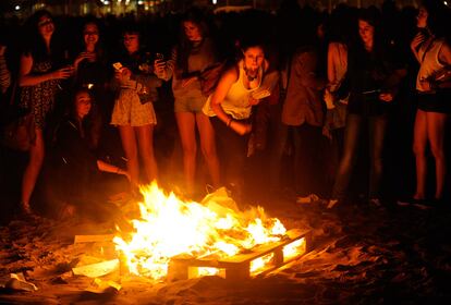 Unos jóvenes mantienen encendida una hoguera en la playa de Poniente en Gijón.