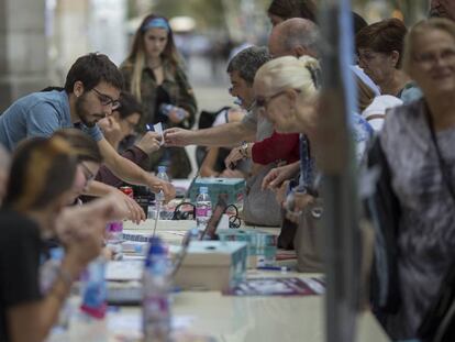 Varios j&oacute;venes universitarios informan con ordenadores y tel&eacute;fonos m&oacute;viles a personas mayores del lugar donde les correspond&iacute;a.